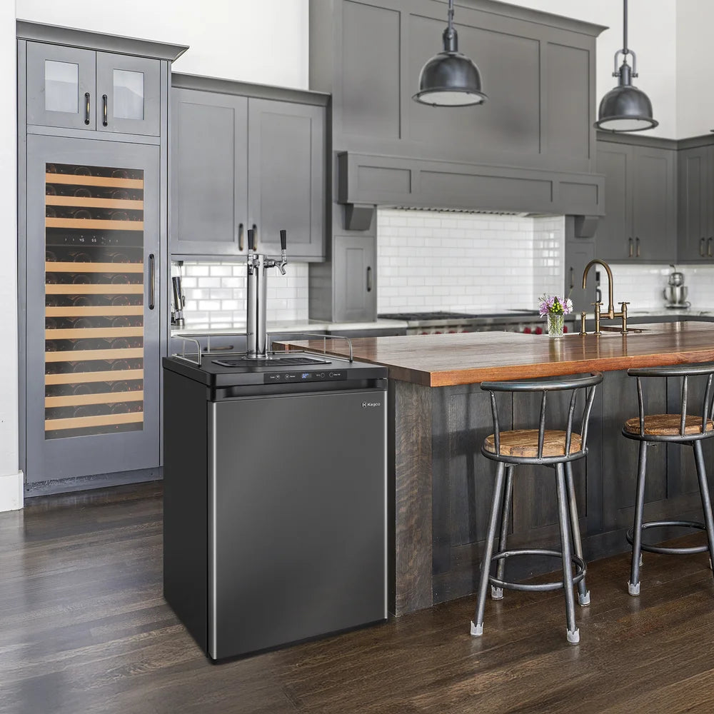 Black stainless Kegco K309 Kegerator installed beside a wood island counter in a grey modern kitchen